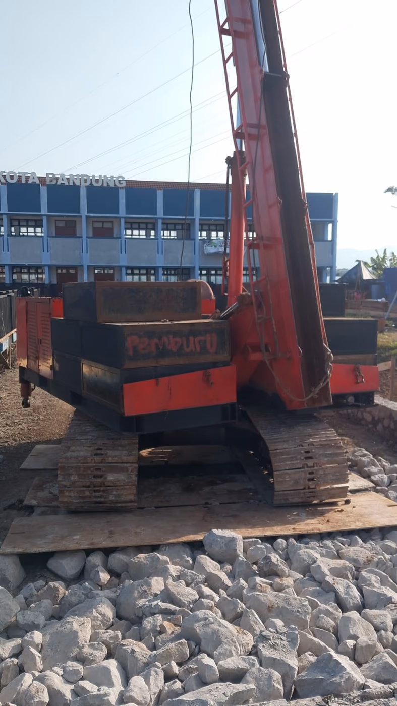 Hydraulic static pile driver di site SMPN 60 Kota Bandung dengan latar bangunan Kota Bandung